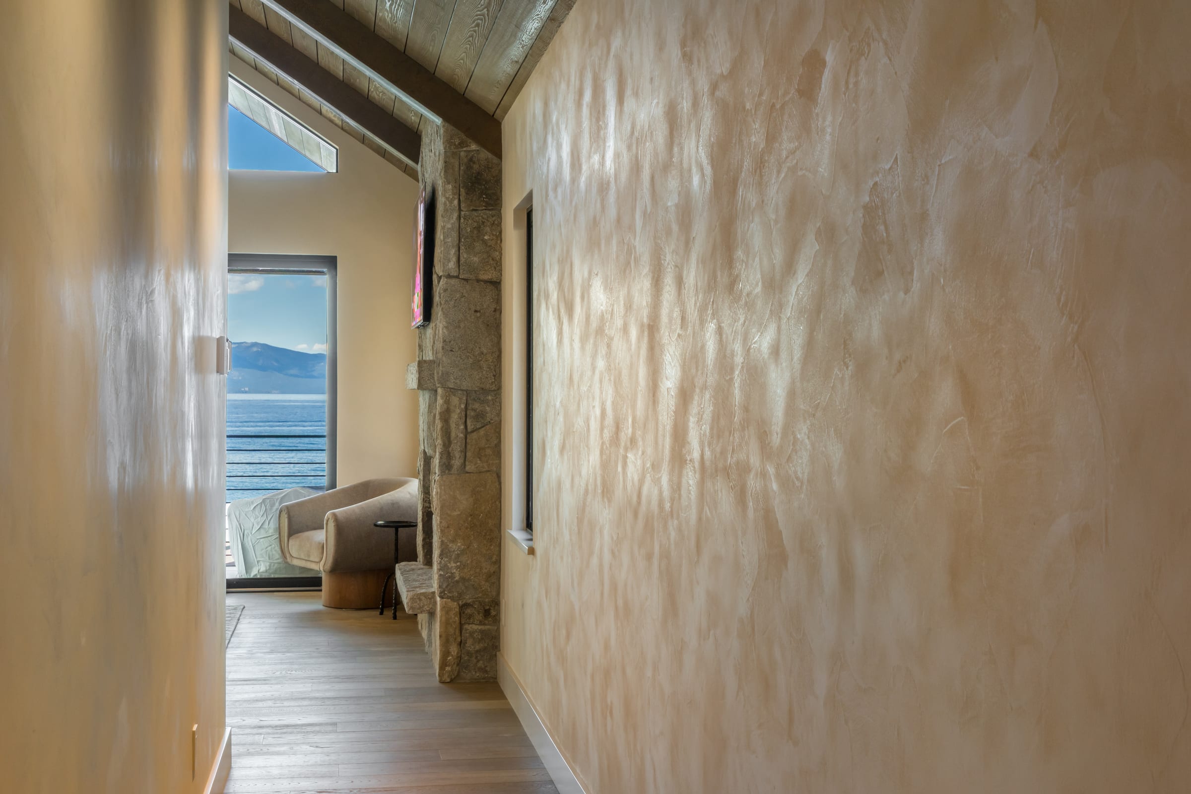 A plaster hallway in a Tahoe home opening onto a lake and mountain view