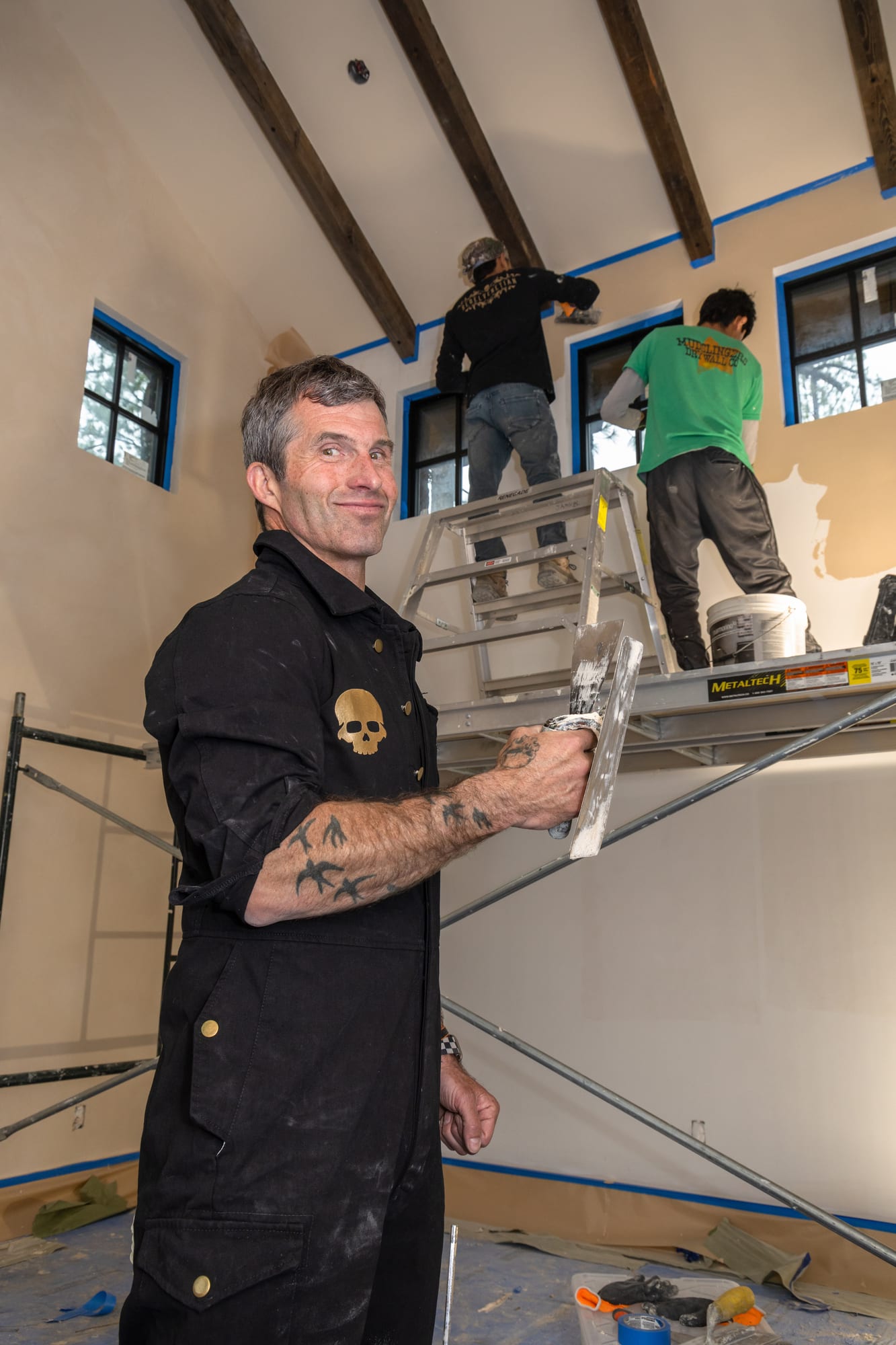 Kyle Railton on a ladder with a crew member working behind him